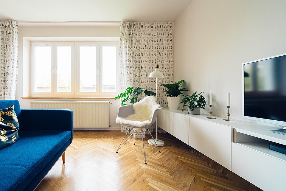 Bright living room with a blue sofa, wooden floor and a large window